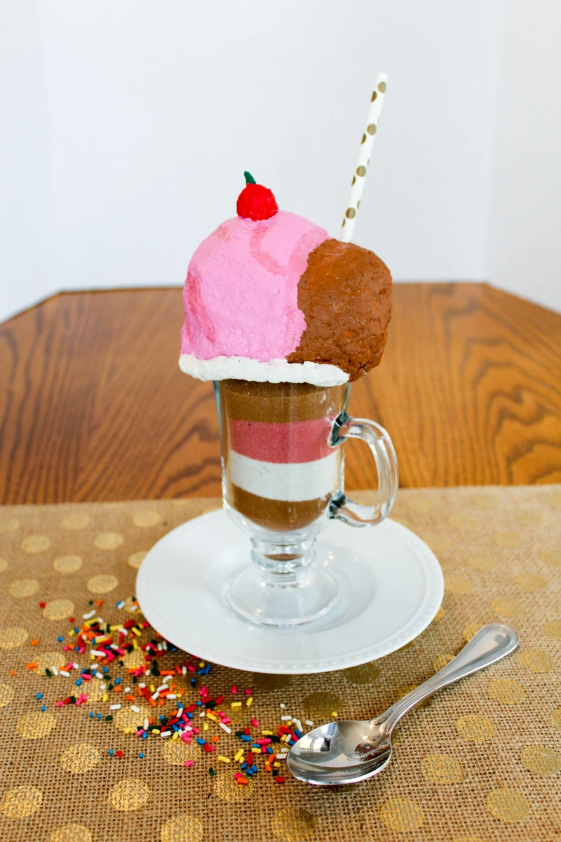 It's so fun to create an ice cream sundae sculpture!  Learn how to use colored sand and paper mache to create a delicious work of art!  #celluclay #sculpture #coloredsand